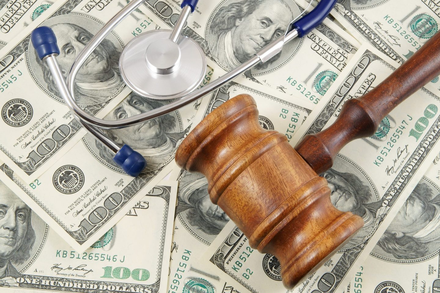 Wooden gavel and stethoscope on us dollars background